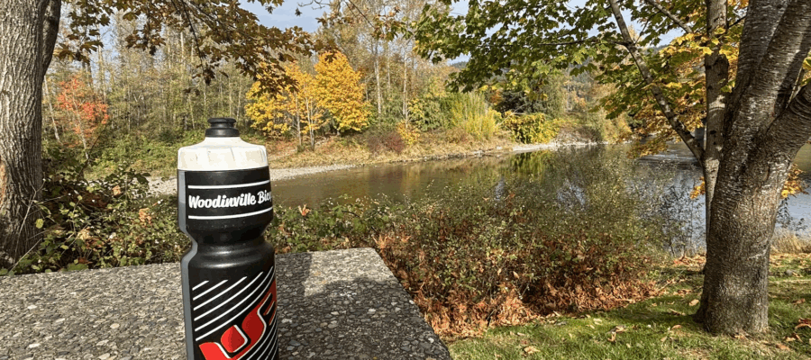 Water bottle on a table with fall foliage in the background.